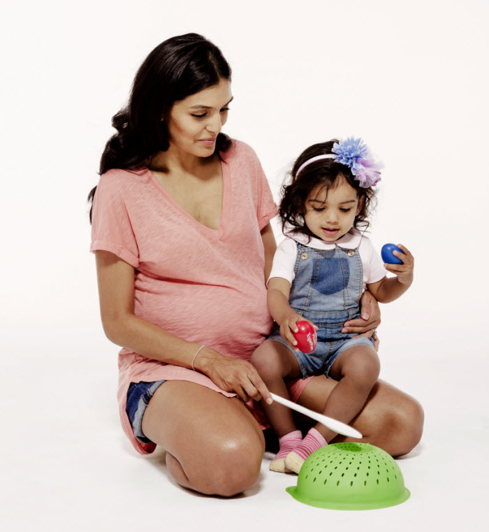 Pregnant mom with toddler daughter, playing kitchen instruments and shakers